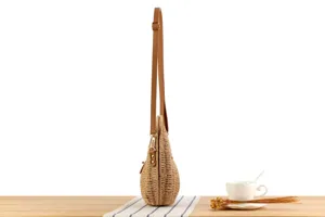 Side profile detail shot of the handmade woven straw shoulder bag with adjustable strap.