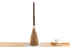 Détail de sac à bandoulière tissé à la main, paille naturelle avec lanière marron réglable.