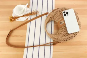 Detailed shot of a woven straw crossbody bag featuring a round ring design and PU leather strap.
