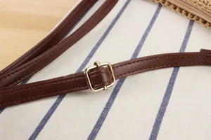 Gros plan sur la bandoulière en cuir marron réglable avec boucle métallique dorée pour sac.