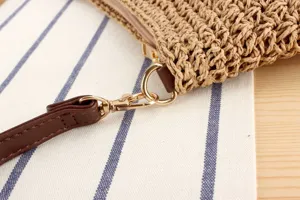 Gros plan sur la lanière de sac en paille tressée et les attaches en métal doré, élégant.