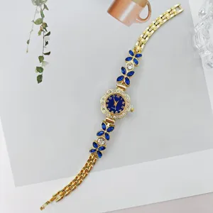 Elegante goldene Damen Quarz Armbanduhr mit blauen Strass Blüten und filigranem Armband Stil.