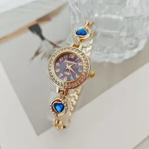 Primo piano di un orologio da polso al quarzo da donna con ciondoli a cuore blu e strass brillanti.