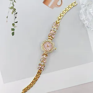 Elegante goldene Damen Quarz Armbanduhr mit rosa Strass Blumen und rosafarbenem Zifferblatt.