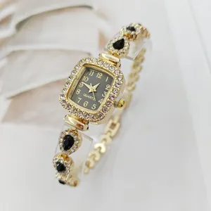 Nahaufnahme einer goldenen quadratischen Strass-Quarzuhr mit schwarzen Tropfenarmband.
