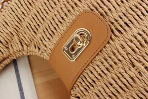 Close-up detail of straw woven crossbody bag with brown PU leather buckle and gold twist lock.