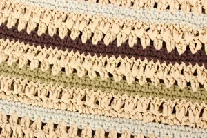 Close-up detail of handmade paper straw and cotton woven shoulder bag with multicolored stripes texture.