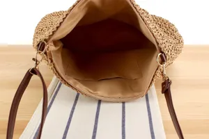 Vue détaillée de l'intérieur du sac à bandoulière en paille tissée avec doublure et poche.