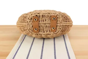 Handmade woven straw shoulder bag bottom detail view, casual beach vacation style accessory.