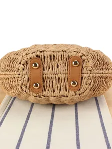 Handmade woven straw crossbody bag bottom view with protective metal feet and leather straps.