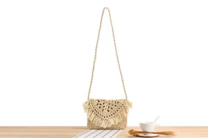 Detailed view of fashionable women straw woven shoulder bag with fringe for casual beach vacation.