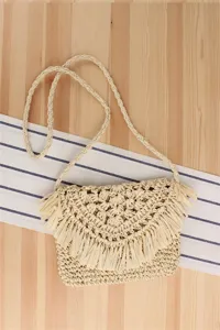 Detailed view of handmade straw woven crossbody bag with fringe flap for summer vacation.