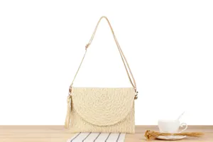 Detail shot of beige straw woven crossbody bag on wooden table with cup and dried flowers