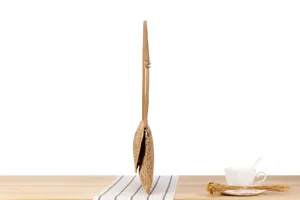 Woven crossbody bag detail, straw texture surface, slim shoulder strap with metal buckle.