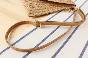 Detail shot of women casual straw woven bag shoulder strap with metal buckle and PU leather.