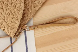 Women woven bag detail featuring natural straw texture and durable leather wrist strap.