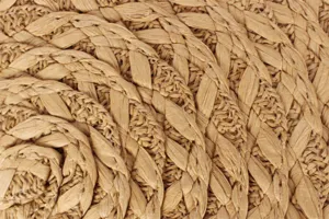 Detailed close-up shot of woven straw bag texture, showing intricate braided craftsmanship.