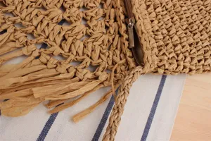 Close-up detail of women's straw woven tassel bag zipper craftsmanship and texture.
