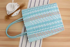 Vista dettagliata della grande borsa a spalla intrecciata in plastica impermeabile casual.