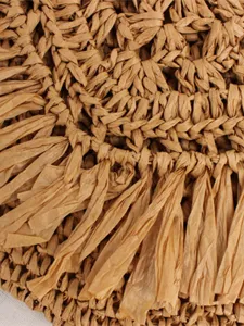 Detailed shot of a stylish straw woven bag with chic fringe design, perfect for casual summer days.