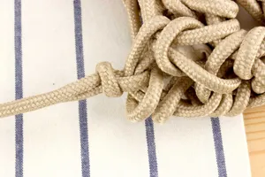 Handmade woven rope knot shoulder bag detail, minimalist casual summer beach handbag style.