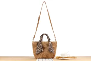Close detail view of handmade straw woven shoulder bag featuring brown strap and zebra scarf.