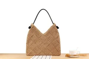 Detalle de bolso tote de paja hecho a mano con diseño triangular único y asa negra.