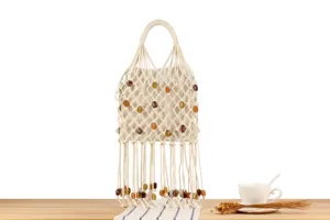 Details of stylish macrame woven handbag with decorative beads and fringe for women fashion.