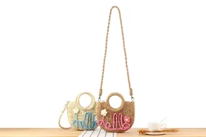 Detailed view of handmade straw woven crossbody bag with cute hello lettering and floral decor.
