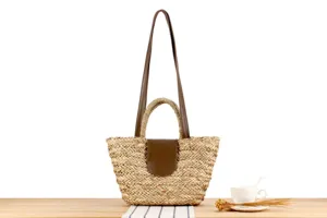 Borsa a tracolla in paglia naturale intrecciata a mano con cinturini in ecopelle e patta.