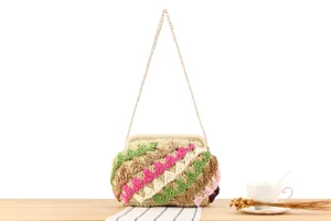 Dettaglio della borsa in paglia artigianale con dettagli crochet colorati e catena.