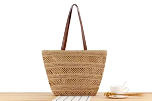 Detailed view of woven straw tote bag with brown leather handles and hollow out texture.