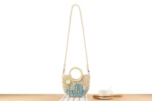 Handmade straw woven crossbody bag with round handle and cute floral details for summer.