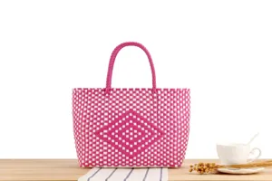 Dettaglio borsa shopper intrecciata rosa e bianca con motivo a rombi, ideale per spiaggia.