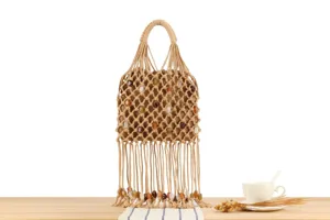 Hollow woven handbag detail featuring delicate beaded fringes and intricate macrame pattern.