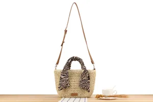 Detail view of handmade straw woven shoulder bag with stylish animal print scarf and leather strap.