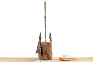 Woven straw bucket bag with brown strap and zebra print scarf detail for casual summer.