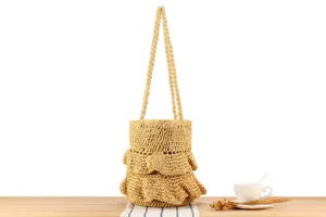 Detailed view of straw shoulder bag with ruffles and double handles for summer beach use.