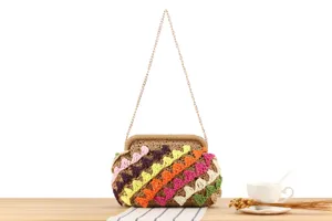 Vista dettagliata di una borsa in paglia intrecciata a mano con onde colorate e catena.