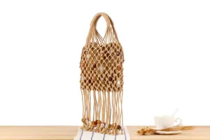 Detail view of beige macrame woven handbag with beaded fringe and handles, unique boho style accessory.
