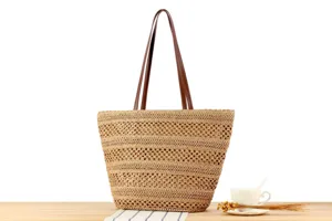 Detail shot of the woven straw tote bag showing intricate cut-out patterns and leather handles.