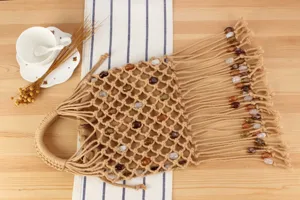 Detail view of beige macrame woven handbag featuring fringe and beaded accents for stylish wear.