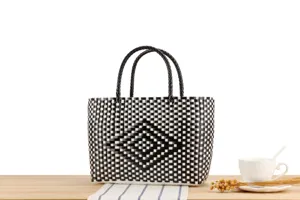 Dettaglio della borsa in plastica intrecciata nera e bianca con motivo a losanghe.