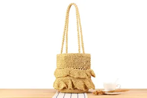 Handmade woven straw shoulder bag detail shot showcasing the delicate tiered ruffle design.
