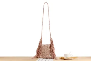 Handmade pink macrame crossbody shoulder bag featuring detailed fringe design and stylish texture.