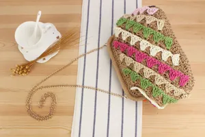 Dettaglio della borsa di paglia intrecciata a mano con pizzo colorato e catena d'oro.
