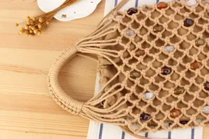 Beaded woven handbag detail shot showcasing intricate mesh design and gemstone accents.