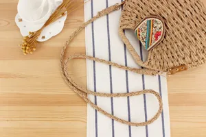 Detailaufnahme der handgeflochtenen Stroh-Umhängetasche mit farbiger Perlenklappe und Riemen.