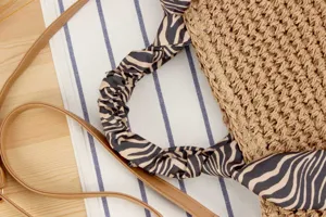 Detailed view of handmade straw woven shoulder bag with zebra print handle and strap.