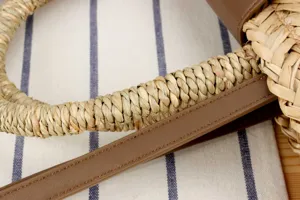 Primo piano del manico di una borsa da donna artigianale in paglia naturale e PU.